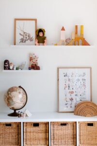 Interior of child room with white wooden furniture with globe and simple toys placed on white shelves and cabinet surface in cozy bedroom